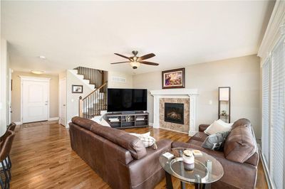 Living room featuring hardwood / wood-style floors, a tiled fireplace, and ceiling fan | Image 2