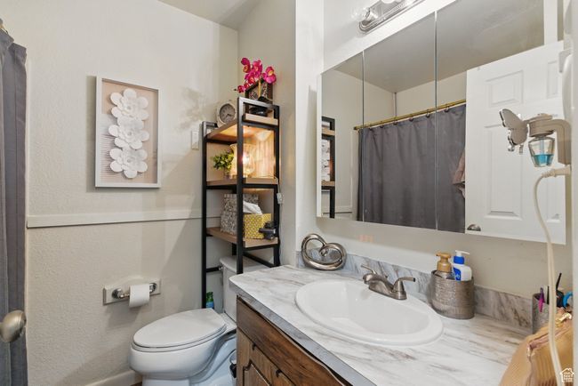 Full bath featuring toilet, vanity, and curtained shower | Image 36