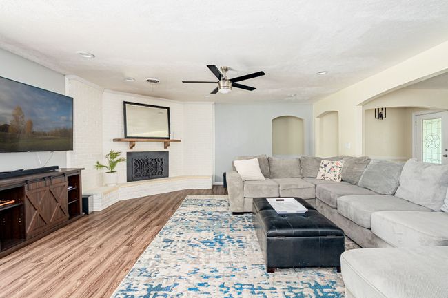 Living room with wood finished floors, ceiling fan, arched walkways, a fireplace, and recessed lighting | Image 26