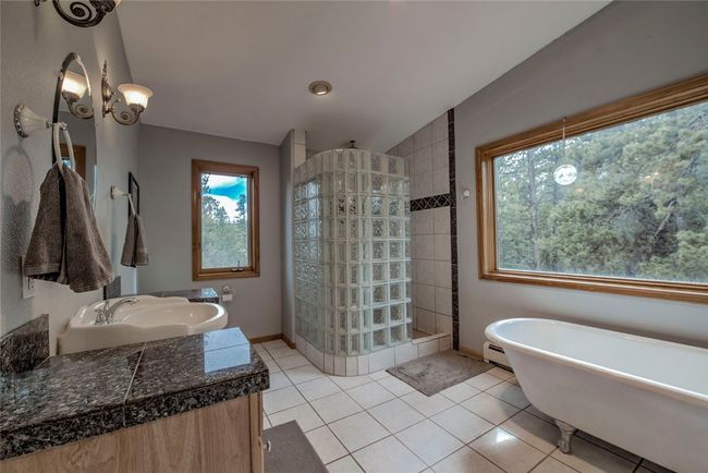 Full bathroom featuring walk in shower, a freestanding bath, vanity, and tile patterned floors | Image 31