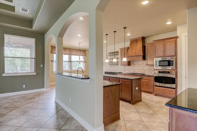 Gourmet Kitchen featuring backsplash, an island with sink, appliances with stainless steel finishes, and custom exhaust hood | Image 10