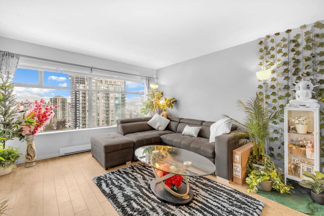 Living area with wood finished floors, a baseboard heating unit, and a city view | Image 12
