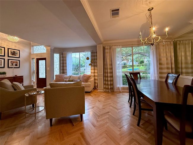 Living room with crown molding, plenty of natural light, a notable chandelier, and visible vents | Image 7