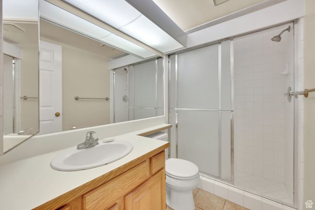 Bathroom with a stall shower, vanity, and tile patterned flooring | Image 6