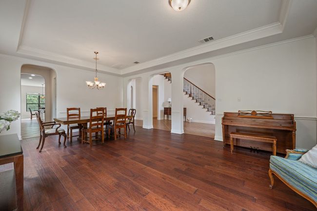 Dining room with visible vents, arched walkways, hardwood / wood-style flooring, and a tray ceiling | Image 19