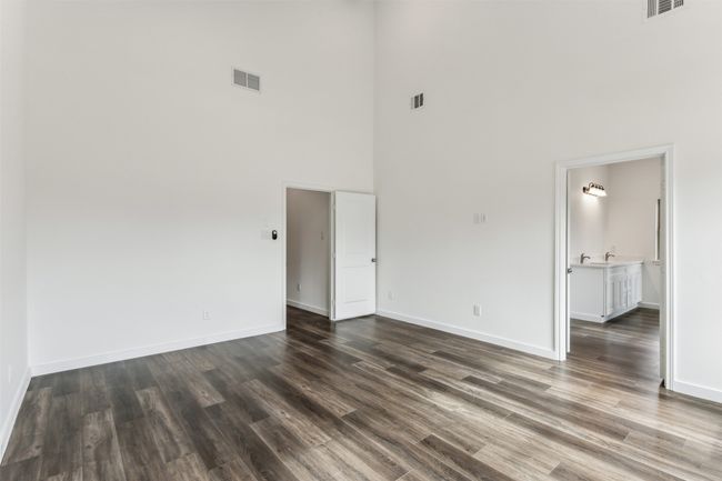 Spare room featuring a towering ceiling and dark wood-style floors | Image 30