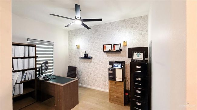 Office with wallpapered walls, light wood-style flooring, and a ceiling fan | Image 7