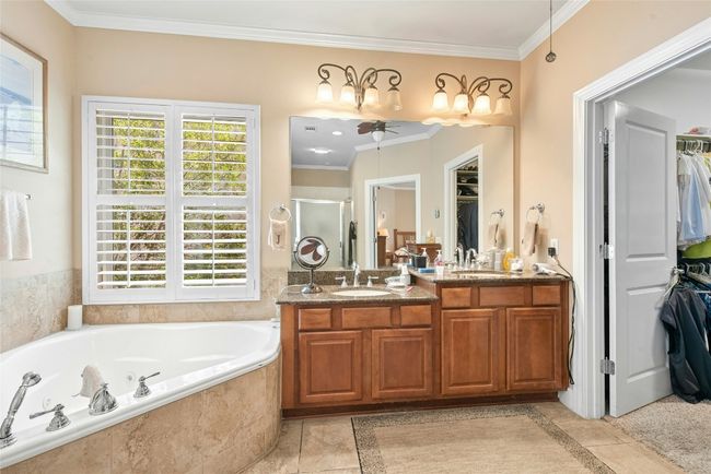 Bathroom featuring ceiling fan, a stall shower, crown molding, a spacious closet, and a garden tub | Image 17