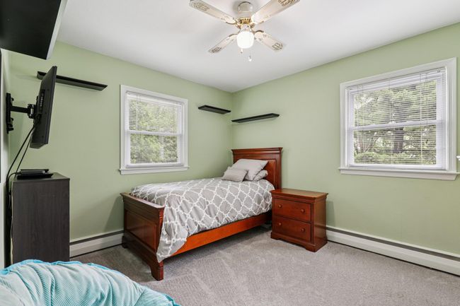 Bedroom featuring multiple windows, baseboard heating, carpet, and a ceiling fan | Image 14