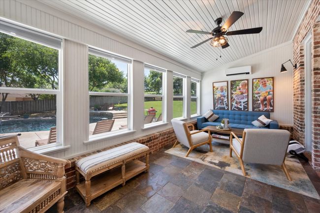 Sunroom featuring an AC wall unit, stone tile flooring, outdoor lounge area, a ceiling fan, and lofted ceiling | Image 12