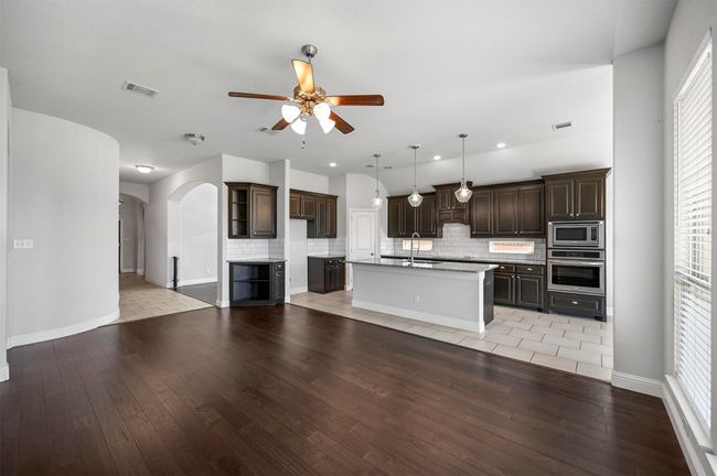 Kitchen with a ceiling fan, visible vents, arched walkways, stainless steel appliances, and dark brown cabinetry | Image 13
