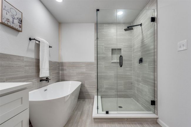 Full bath featuring a stall shower, a soaking tub, tile walls, vanity, and recessed lighting | Image 17