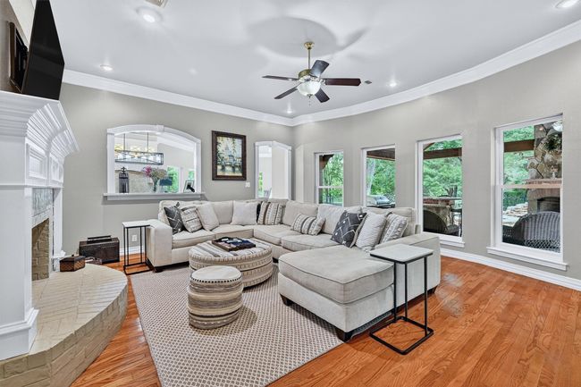 Living room with a brick fireplace, light wood finished floors, a ceiling fan, recessed lighting, and crown molding | Image 9