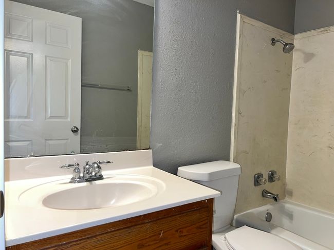Bathroom featuring bathtub / shower combination, vanity, and a textured wall | Image 13