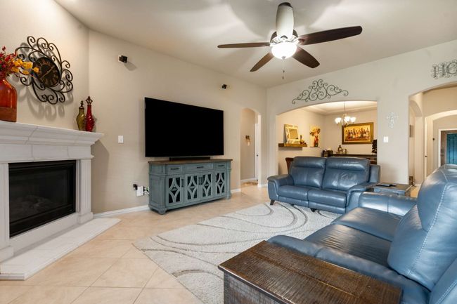 Living area featuring arched walkways, a glass covered fireplace, light tile patterned floors, and ceiling fan | Image 7
