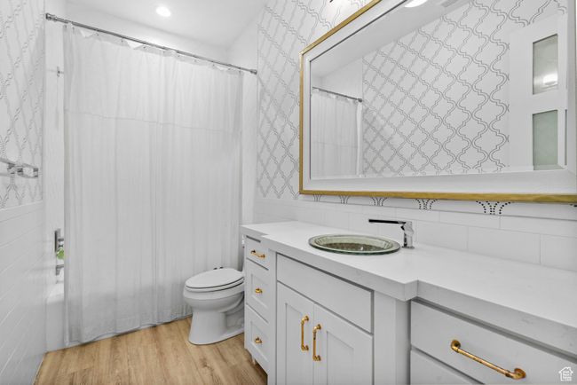 Full bathroom featuring vanity, wallpapered walls, backsplash, toilet, and wood finished floors | Image 72