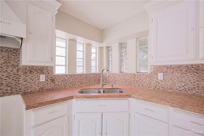 Kitchen with a wealth of natural light, extractor fan, backsplash, and a sink | Image 11