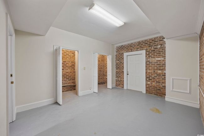 Unfurnished bedroom with brick wall, finished concrete floors, and baseboards | Image 36
