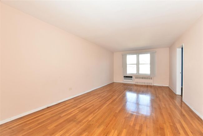 Spare room featuring light wood-type flooring, radiator, and a wall mounted AC | Image 12