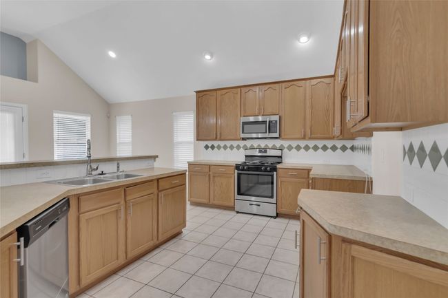 Kitchen featuring stainless steel appliances, tasteful backsplash, light countertops, light tile patterned floors, and recessed lighting | Image 16