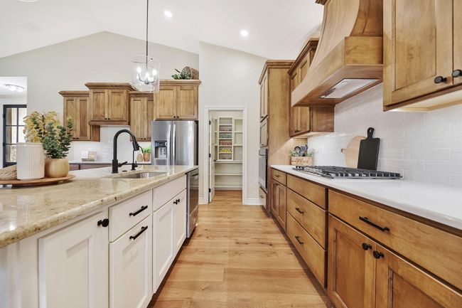 Kitchen with light hardwood / wood-style floors, white cabinetry, vaulted ceiling, premium range hood, and sink | Image 15
