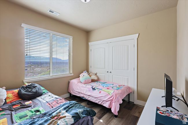 Bedroom with dark wood-style flooring, visible vents, baseboards, and a closet | Image 9