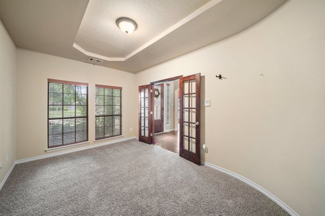 Carpeted empty room with baseboards, visible vents, french doors, and a raised ceiling | Image 23
