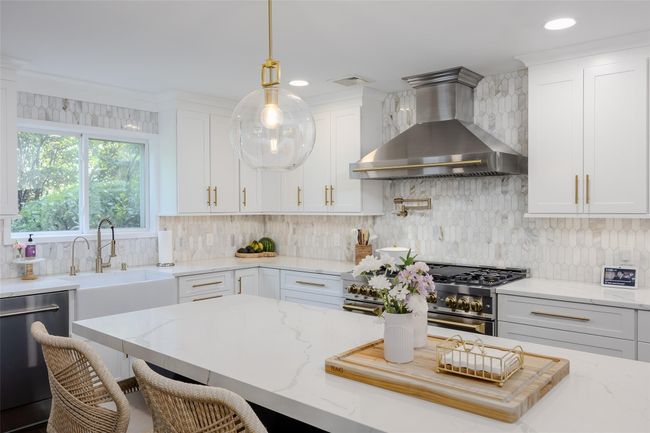 Kitchen with wall chimney range hood, dishwasher, high end stove, white cabinetry, and recessed lighting | Image 4