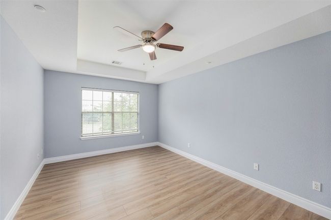 Unfurnished room featuring a raised ceiling, ceiling fan, and light wood-style flooring | Image 20