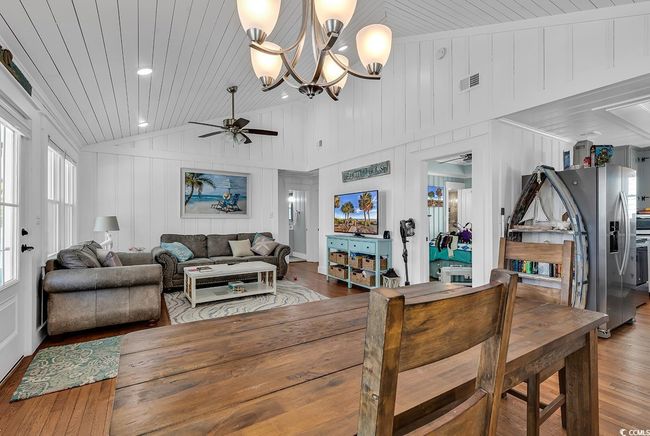 Living room featuring high vaulted ceiling, wood-type flooring, ceiling fan with notable chandelier, and wooden ceiling | Image 4