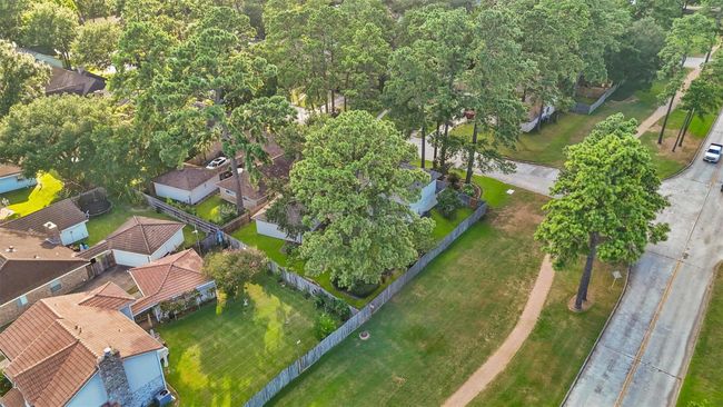 Charming neighborhood with spacious yards and mature trees. Houses feature varied roof styles and ample greenery. Ideal for families seeking a peaceful, natural setting. | Image 27