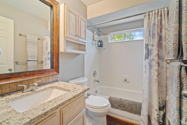 Full bathroom featuring shower / bath combo, vanity, toilet, and backsplash | Image 16