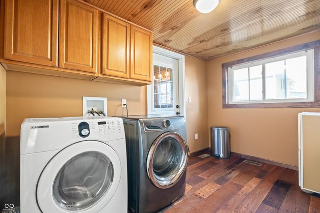 washroom featuring dark wood finished floors, washing machine and clothes dryer, cabinet space, and wooden ceiling | Image 49