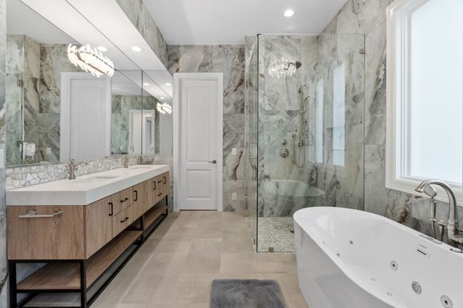 Soaking tub and separate walk-in shower in this stunning main-level primary bathroom. | Image 15