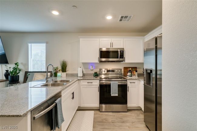 Kitchen with a peninsula, light wood-type flooring, visible vents, a sink, and stainless steel appliances | Image 15