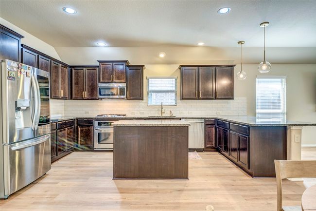 Kitchen featuring stone countertops, plenty of natural light, dark brown cabinets, appliances with stainless steel finishes, and a sink | Image 13