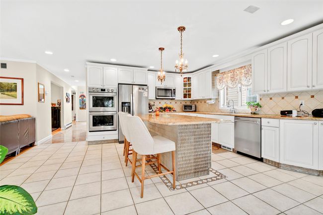 Kitchen featuring appliances with stainless steel finishes, light tile patterned floors, backsplash, recessed lighting, and a breakfast bar area | Image 16