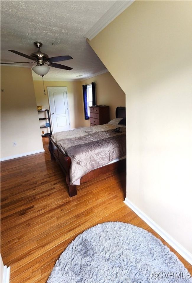 Bedroom with crown molding, wood finished floors, a textured ceiling, and ceiling fan | Image 23