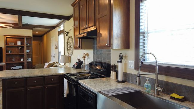 Kitchen with a peninsula, black appliances, under cabinet range hood, a sink, and beam ceiling | Image 26