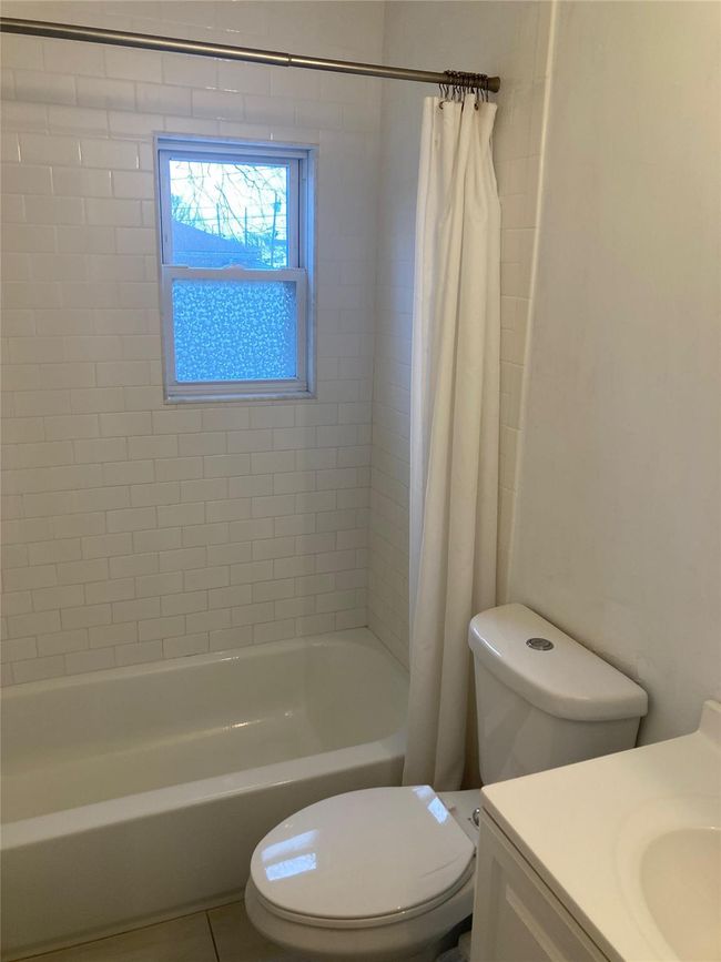 Full bath featuring shower / bathtub combination with curtain, vanity, toilet, and tile patterned flooring | Image 4