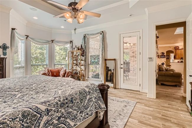 Bedroom featuring crown molding, light wood-style flooring, arched walkways, a ceiling fan, and access to outside | Image 20