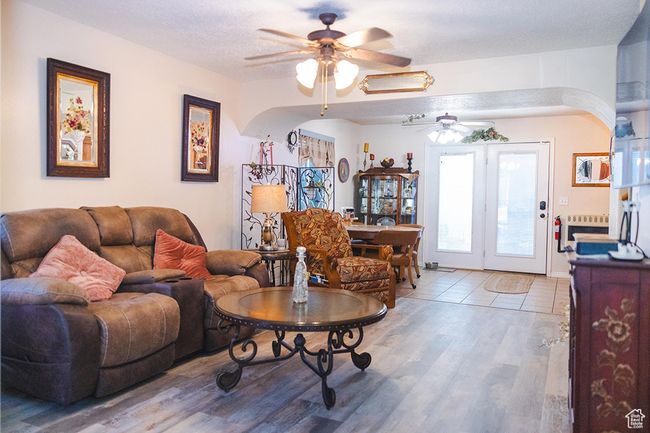 Living area featuring a ceiling fan, wood finished floors, and arched walkways | Image 10