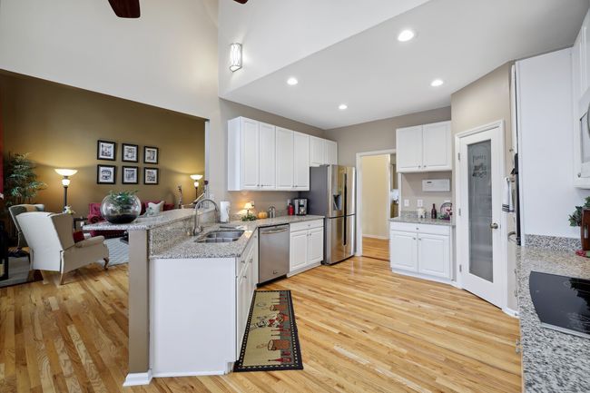 Bright white cabinets, stainless appliances and granite counters grace the open kitchen. Custom pantry door and shelving in pantry too! | Image 10