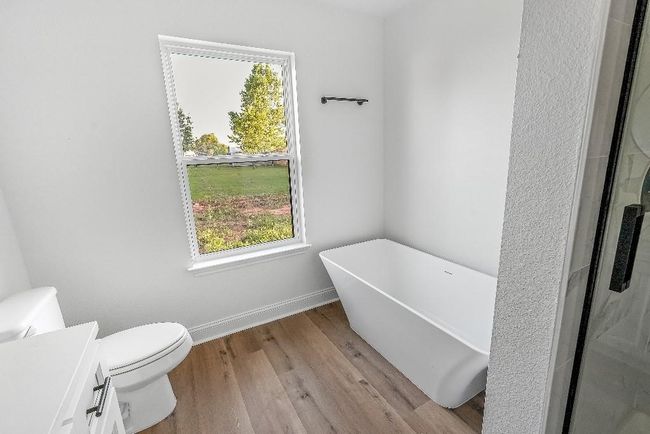Bathroom with wood finished floors, a wealth of natural light, toilet, and a soaking tub | Image 17