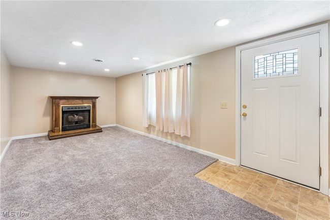 Carpeted entrance foyer featuring baseboards, recessed lighting, and a fireplace with raised hearth | Image 30