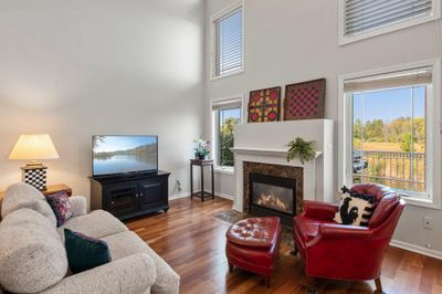 Step into this breathtaking living room, showcasing rich cherry hardwood floors that extend throughout much of the main level, soaring 18-foot ceilings, and an elegant gas-burning fireplace. | Image 3