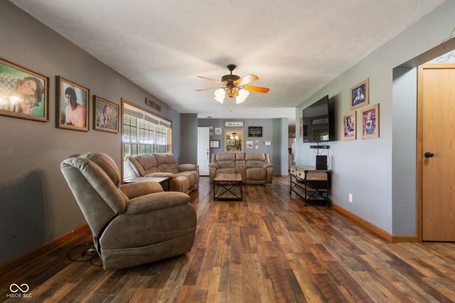 living area with dark wood finished floors, baseboards, a textured ceiling, and ceiling fan | Image 14