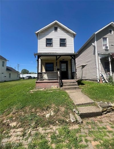 View of front of home featuring a porch and a front​​‌​​​​‌​​‌‌​‌‌​​​‌‌​​‌‌​‌​​​​​‌ lawn | Image 1