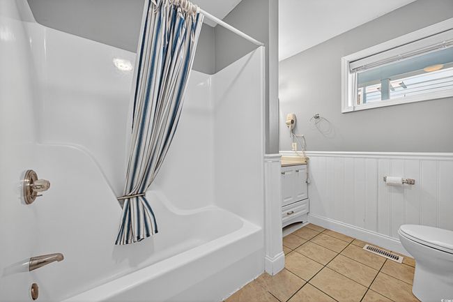 Bathroom featuring shower / bath combination with curtain, tile patterned floors, vanity, and wainscoting | Image 28