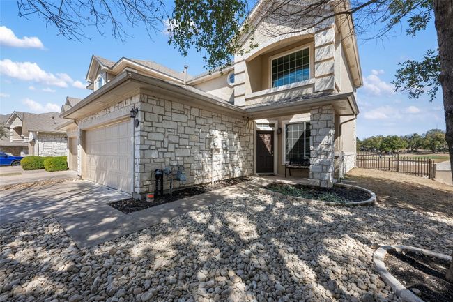 View of front facade featuring stone siding, an attached garage, fence, and driveway | Image 32
